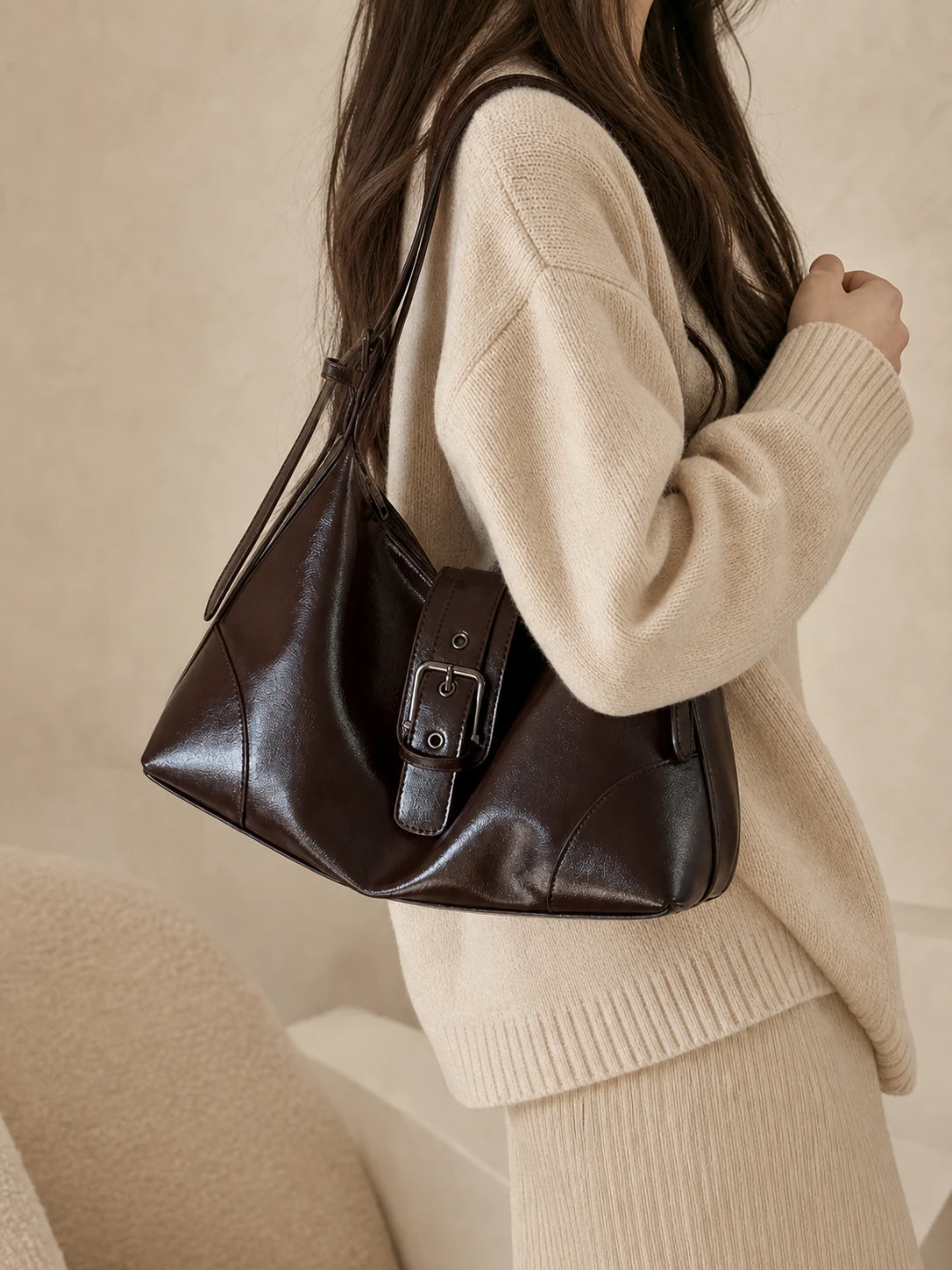 Dark brown underarm shoulder bag worn with a neutral knit outfit