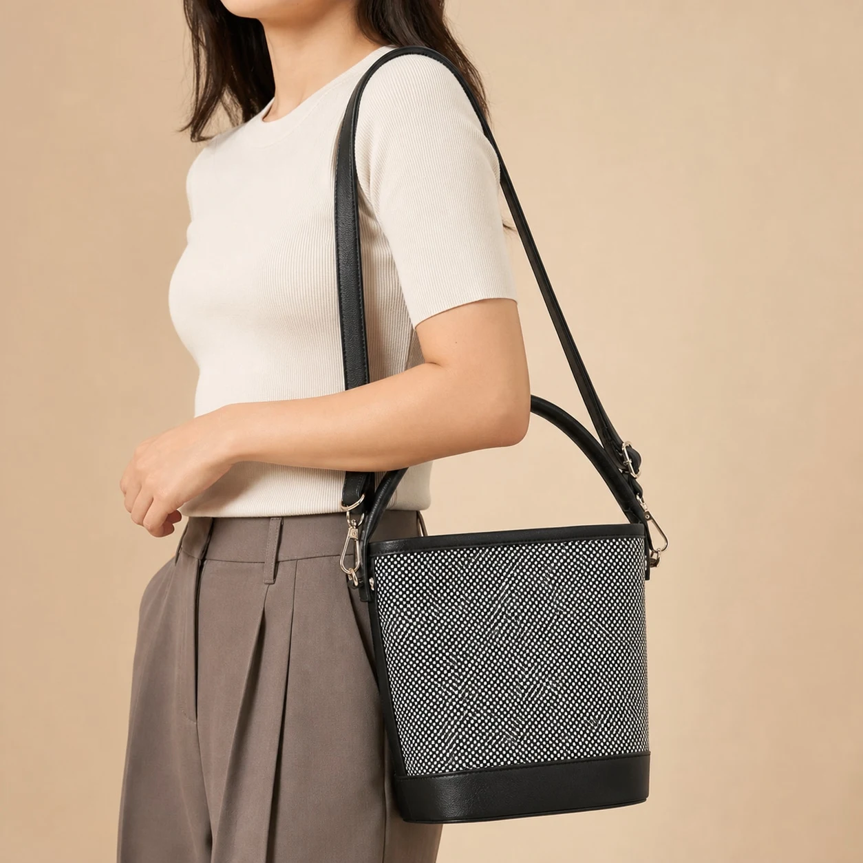 Black and white woven bucket bag worn on the shoulder